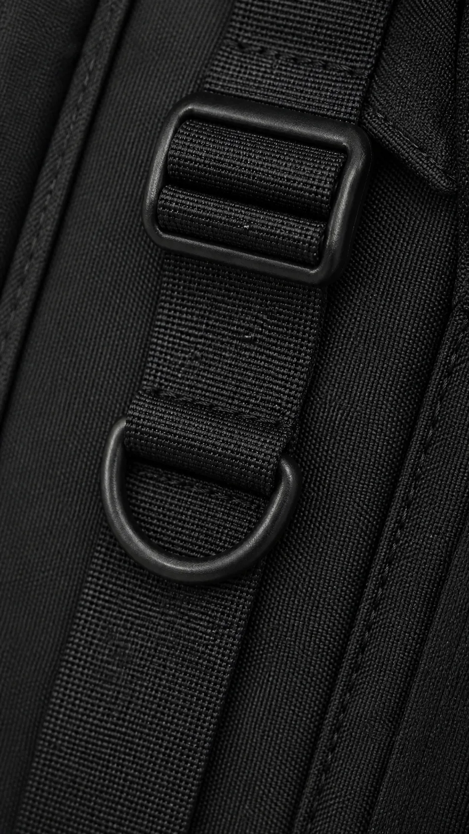 Photorealistic matte-black metal ladder-lock adjuster and D-ring on black woven technical backpack webbing